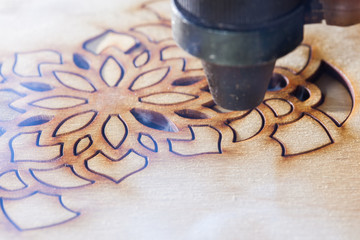 The laser cuts out a tree in the form of a mandala 