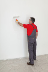 Adult worker painting wall to white with paint roller