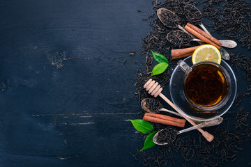 Tea in a glass cup with spices and herbs. On a black wooden background. Top view. Copy space.