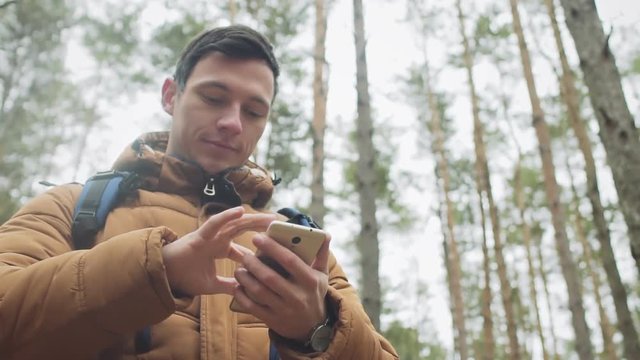 Young man traveler using smart phone in winter forest