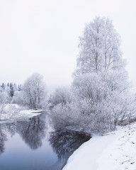 Winter landscape with frosty trees and peaceful river at evening in Finland