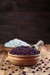 Beans red in a wooden bowl standing on the kitchen table made of oak. 