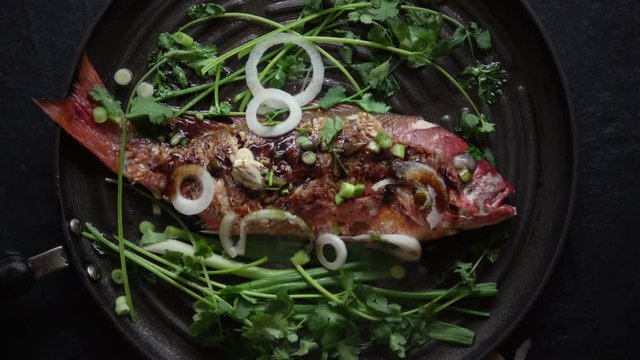 Grilled Whole Red Snapper with Ginger Soy Sauce and Garnish. Served hot in the Frying Pan.