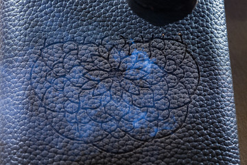 The laser makes engraving in the form of a mandala on the skin