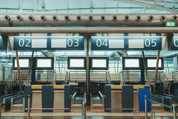Check-in area in modern airport: luggage accept terminals with baggage handling belt conveyor systems, multiple blank white information LCD screen mockups, indexed check-in desks with captions above