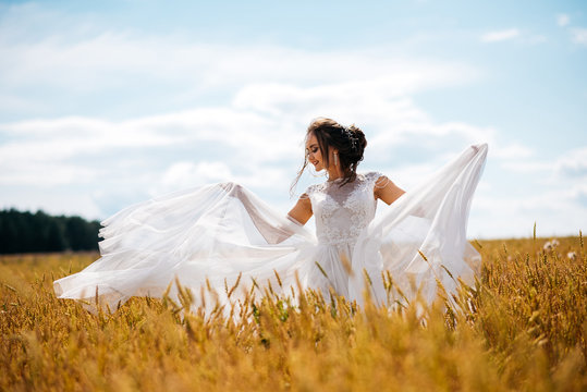 Beautiful Bride In Wedding Dress Is Dancing Alone In A Field Of Wheat And Smile