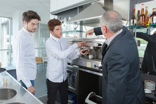 young workers learning how to clean a coffee machine