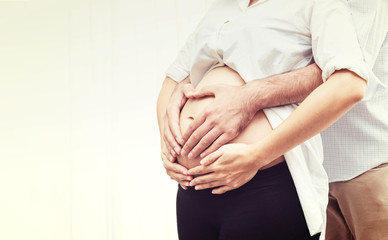 Cluse Up Beautiful Pregnant Woman and Husband Hugging the Tummy with Love - Family Concept