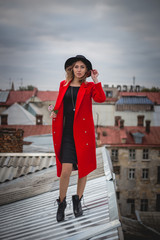 Fototapeta premium Girl in red posing on the roof of old city