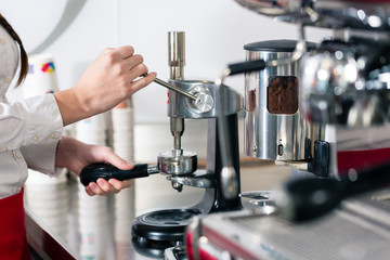 Close-up of the hands of a waiter preparing espresso at an automatic coffee machine