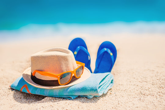 Fototapeta Sandy beach with towel, hat  and summer accessories with copy space.   Vacation and travel items. Tropical Holiday Background