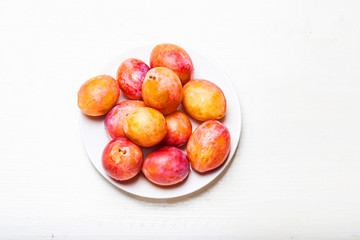 Ripe Yellow Plums on white table top view. Fresh plumps with copy space.
