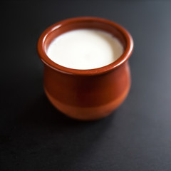 Sour  cream or natural  Cottage cheese curd in clay pot on dark  background. Traditional Cuajada yogurt cream