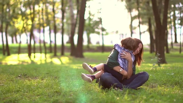 Happy mother hugging her son in the park, slow motion