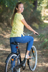 Naklejka premium woman riding a bike in the forest