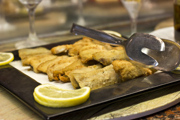 Fillet of fish in breading, fried on a grill. Decorated with slice of lemon.