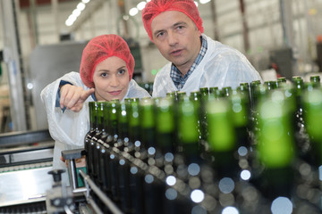 workers checking a conveyor bottles belt in factory