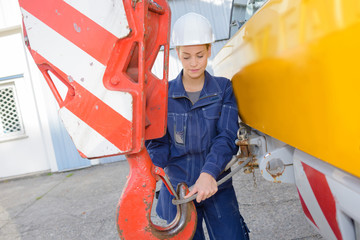 Woman attaching cable to winch of crane