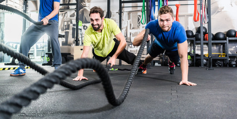 Men with battle rope in functional training fitness in gym