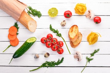 Food. Baguette, pasta, quail eggs, fresh vegetables. On a white wooden background. Top view. Copy space.
