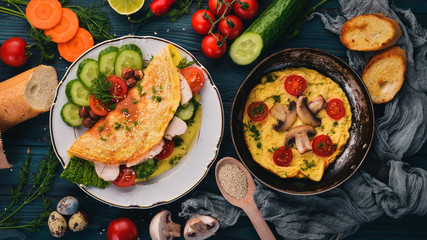 A set of omelets with vegetables, mushrooms and chicken. On a wooden background. Top view. Copy space.