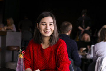 Happy young woman drinking coffee / tea and using tablet computer in a coffee shop