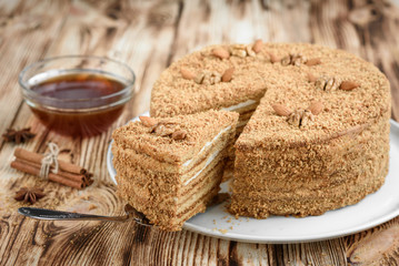 Код стоковой фотографии без лицензионных платежей — 781481086 Homemade layered honey cake with nuts and slice of cake on white plate on wooden table