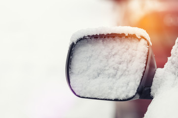 The car is all covered with snow. Snow on rearview mirror. Concept of driving in winter time with snow on road. Toned photo with copy space.