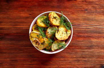 Fried potatoes with salt, dill, lemon and spices on a wooden Board on brown background with copy space. The view from the top