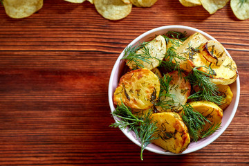 Fried potatoes with salt, dill, lemon and spices on a wooden Board on brown background with copy space. The view from the top