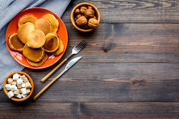 Make fluffy pancakes. Ingredients, cakes and toppings like nuts and honey on dark wooden background top view copy space