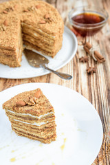 Код стоковой фотографии без лицензионных платежей — 781481086 Homemade layered honey cake with nuts and slice of cake on white plate on wooden table