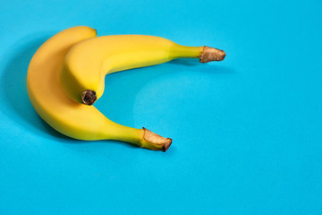 Fresh bananas close up on bright blue background. Flat lay. Summer concept.