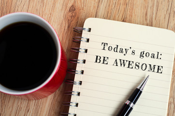 Today's goal - Be awesome text on notepad with pen and a cup of coffee, wooden background