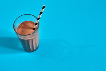 Glass of chocolate milk on blue background