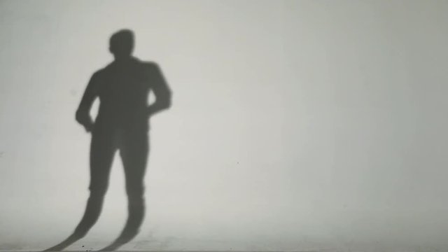 Sexy man's shadow on the wall. He comes by walking and getting naked figure.