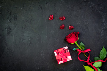 Gift for Valentine's day. Red rose, gift box, red hearts signs on black background top view copy space