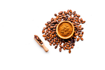 Main ingredient for chocolate. Cocoa powder in bowl near cocoa beans on white background top view copy space