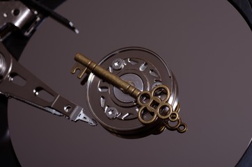 Data security concept. Bronze key on spindle of a hard disk drive.