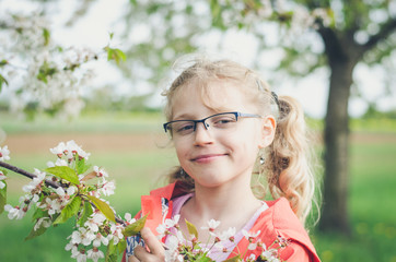 happy smiling girl in glasses and blossoming twig of tree
