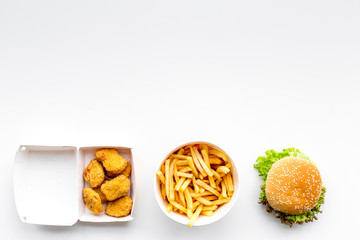 Fast food. Chiken nuggets, burgers and french fries on white background top view space for text