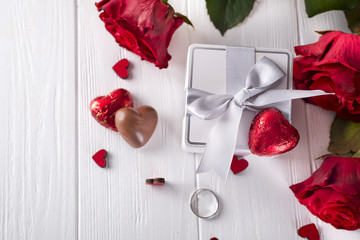 Fototapeta na wymiar Fresh red roses and gift box on wooden table