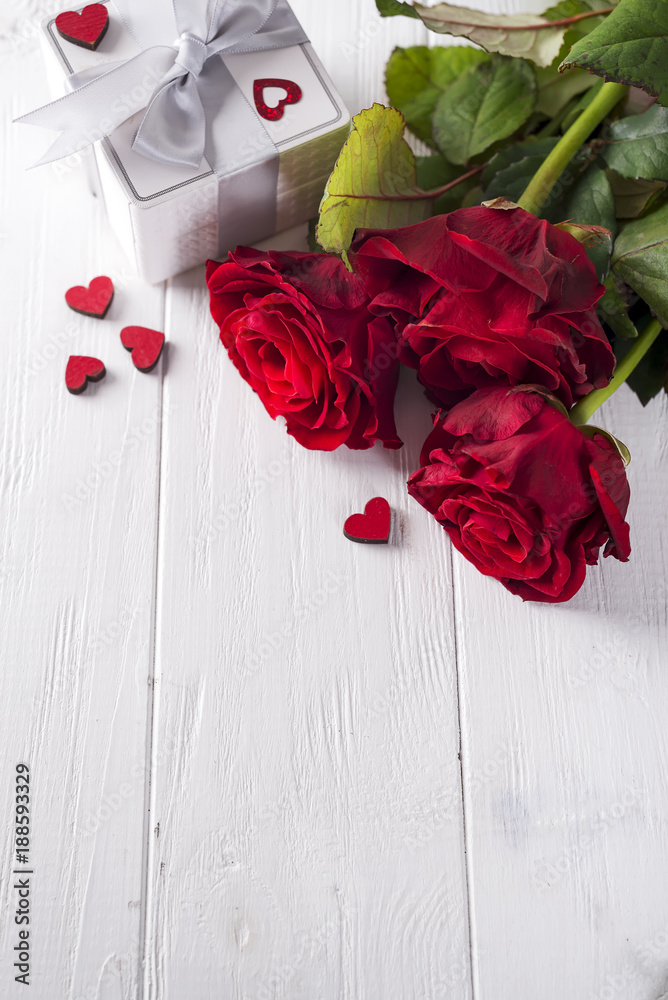 Wall mural Valentines concept with bouquet of roses and wrapped gift on wooden table