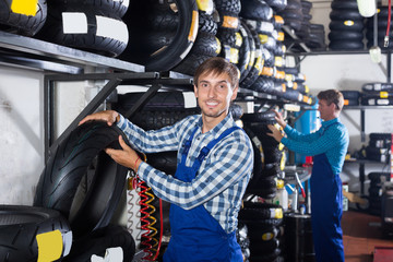 Fototapeta na wymiar Adult working man standing with new tires
