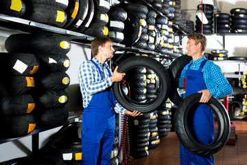 Fototapeta na wymiar Two male professionals standing with new tires