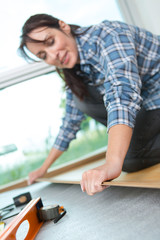 repairwoman laying laminate flooring at home