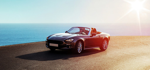 Young couple riding a luxurious convertible - obrazy, fototapety, plakaty