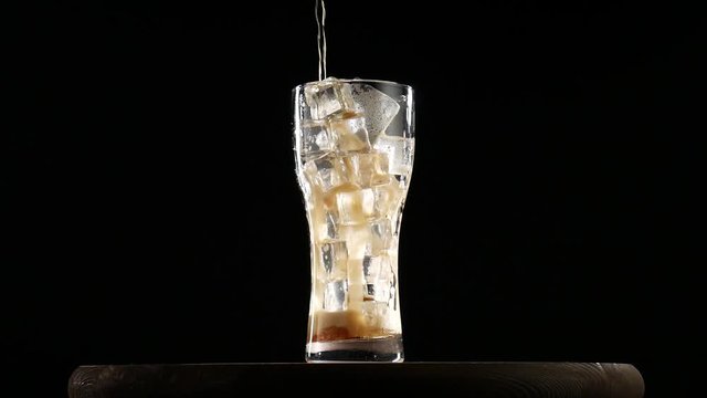 Cola pouring in glass with ice. Glass of cold coke with ice cubes.