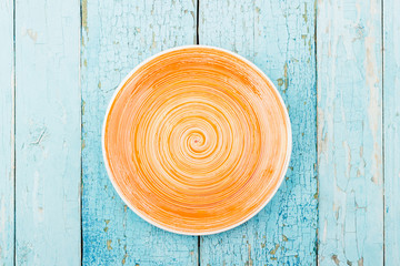 Orange ceramic plate on the blue wooden background