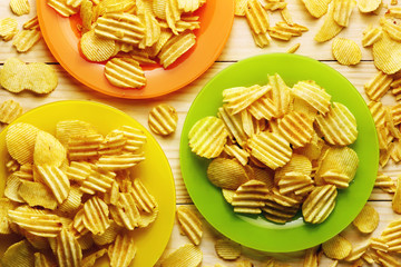A lot of crisps potato in the colorful plates on a wood